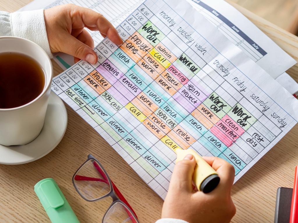 woman's hands holding a schedule with times blocked our in colours